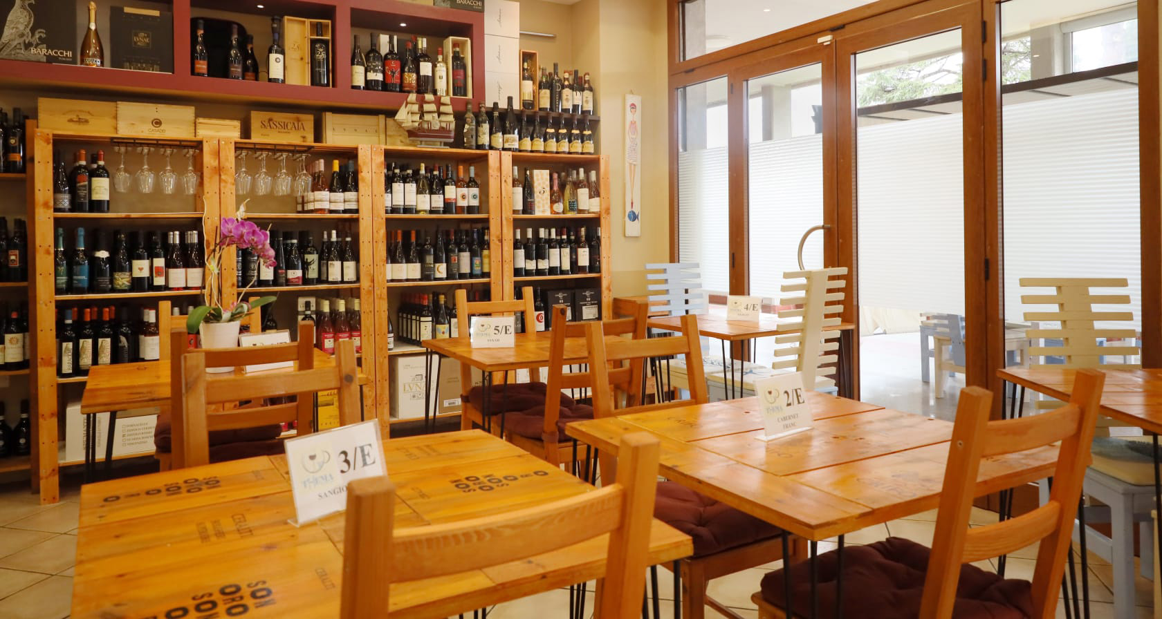 La sala dell'enoteca di THEMA a Marina di Castagneto Carducci, con le pareti di bottiglie